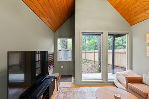 A living room with a television, a sofa, and a large sliding glass door leading to a backyard.