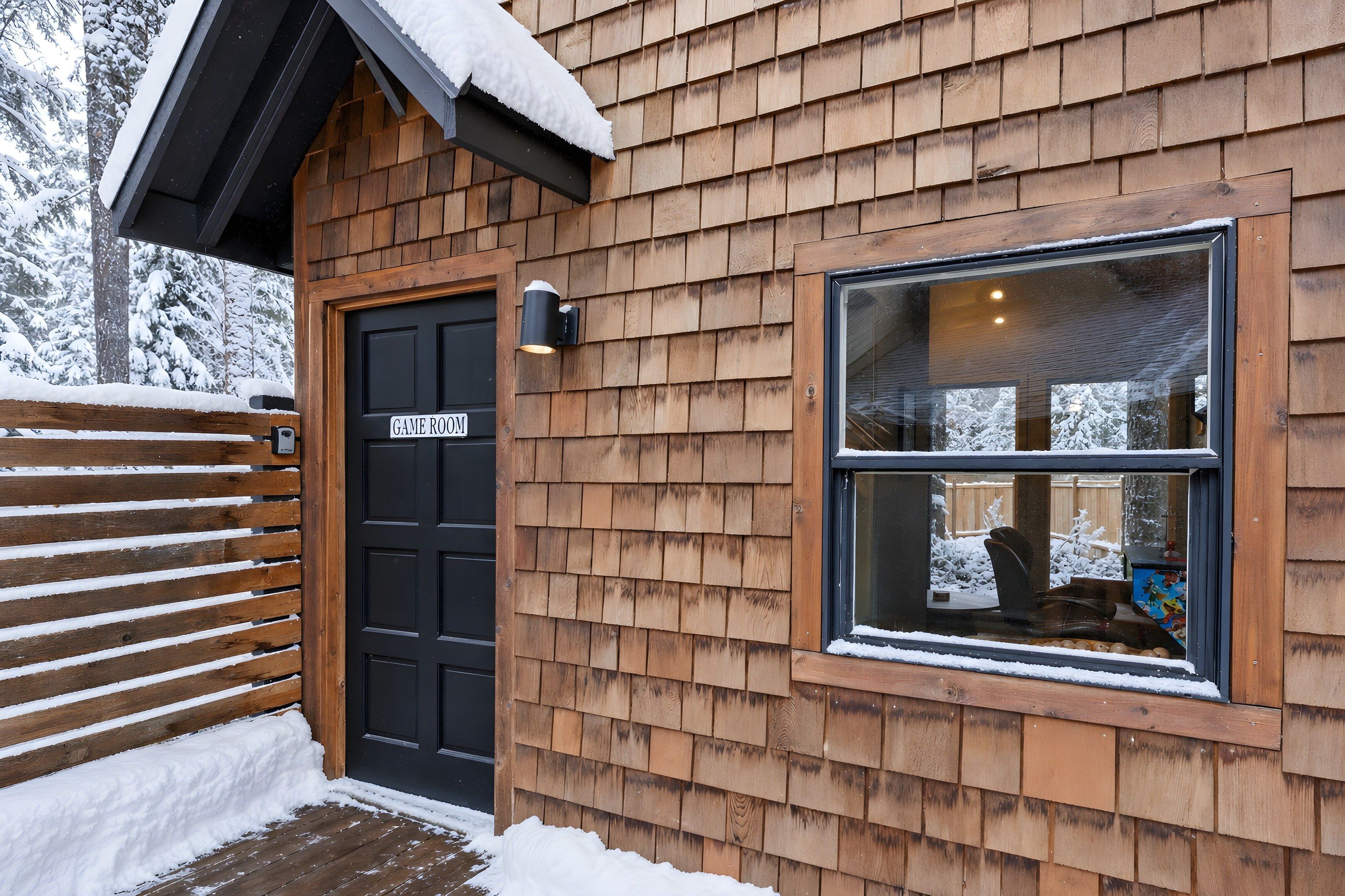 A wooden exterior with a black door labeled 'GAME ROOM' and a window with a view of a snowy landscape.