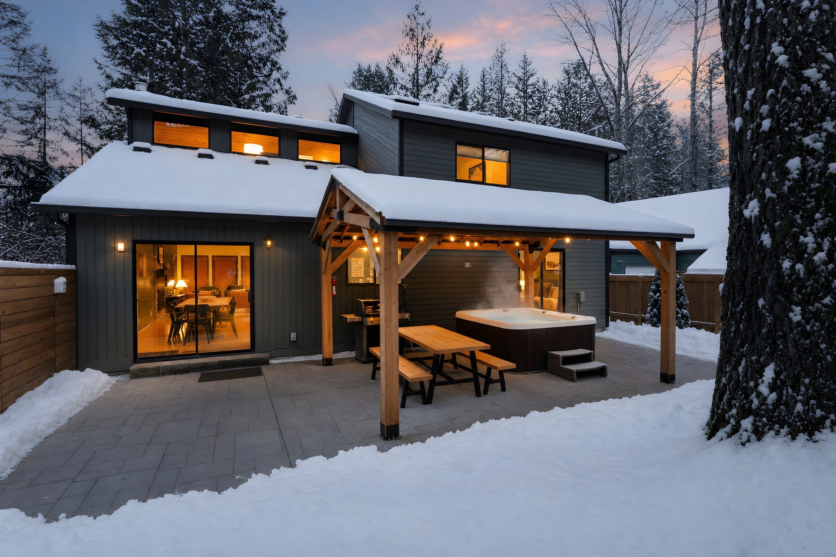 Ein modernes Haus mit einer überdachten Terrasse, einem Whirlpool und einem Essbereich.