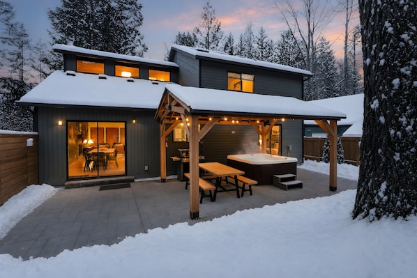 A modern house with a covered patio, a hot tub, and a dining area.