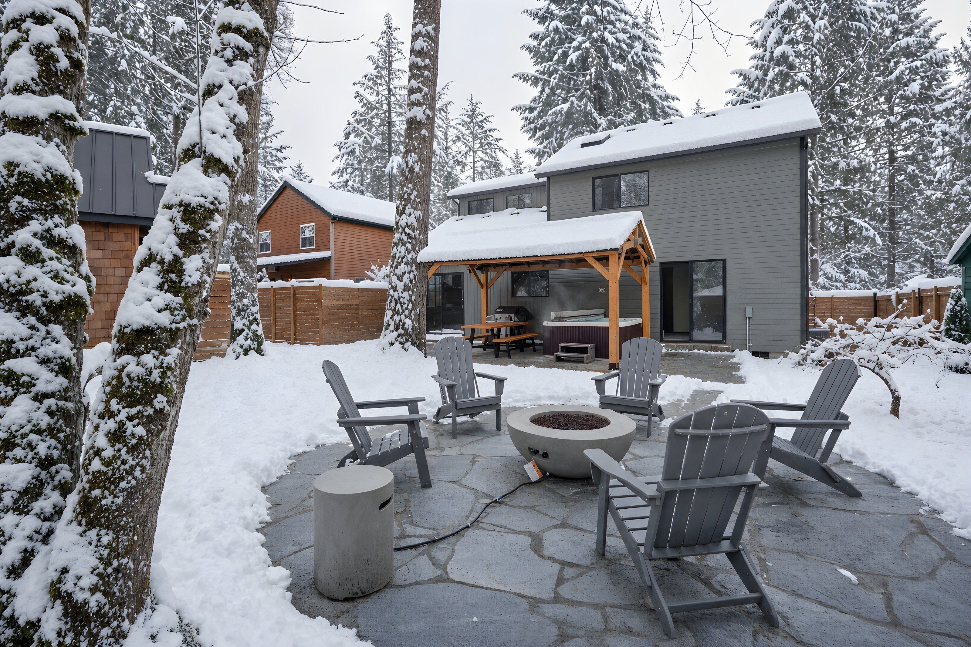 Eine Terrasse mit Adirondack-Stühlen, einem Feuerkorb und einem überdachten Sitzbereich.