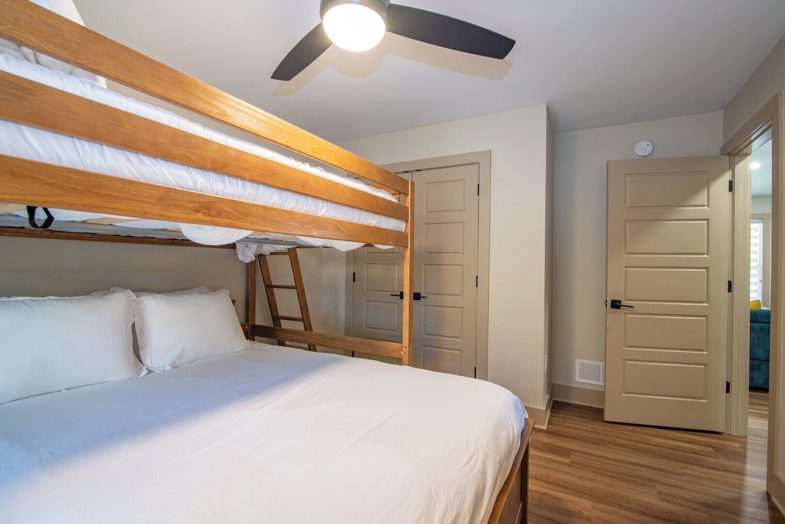 A bunk bed room with a ceiling fan, a ladder, and two doors.