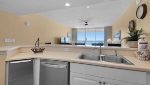 A kitchen with a built-in dishwasher, a double sink, and a ceiling fan. - 🏖️Beach Chair Service Included-Beachfront @ Majestic Beach-Amazing View! (Panama City Beach)