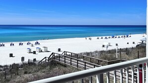 A beach with white sand, clear blue water, and a wooden boardwalk leading to the beach. - 🏖️Beach Chair Service Included-Beachfront @ Majestic Beach-Amazing View! (Panama City Beach)