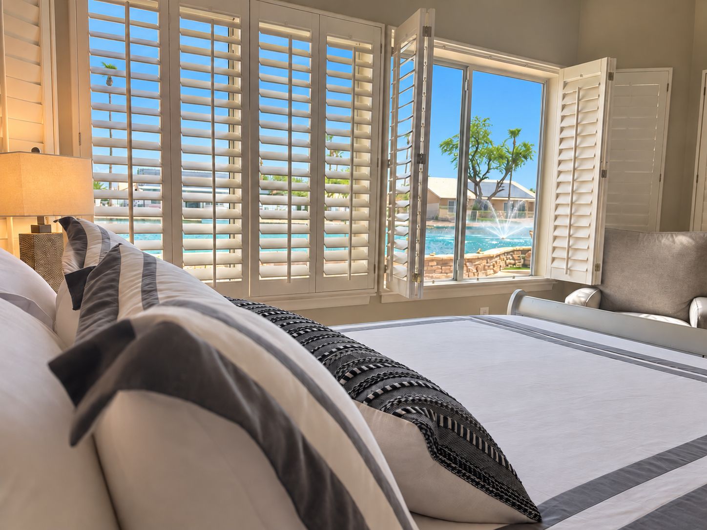 Une chambre d’hôtel avec un lit, une chaise et une vue sur une piscine et des palmiers.