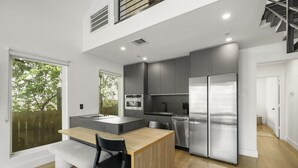 A modern kitchen with a central island, stainless steel appliances, and a view of greenery outside. - O`Four Lofts North, Unit A (Houston)