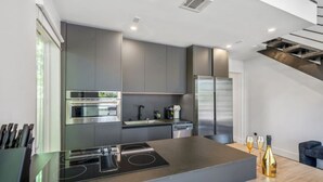 A modern kitchen with a central island, stainless steel appliances, and a sleek design. - O`Four Lofts North, Unit A (Houston)
