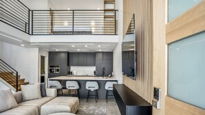 A modern interior with a living area, kitchen, and a mezzanine level. - The O'Four Lofts Cabin, Unit C (Houston)