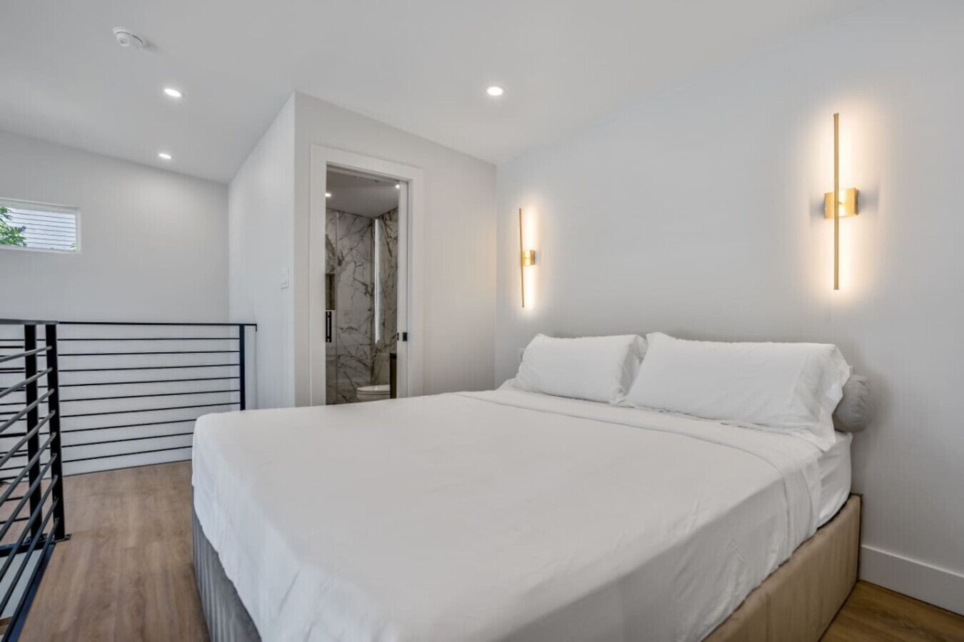 A modern bedroom with a large bed, a wooden headboard, and two wall-mounted light fixtures.