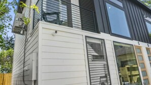A modern two-story house with a balcony, large windows, and a garage. - The O'Four Lofts Cabin, Unit C (Houston)