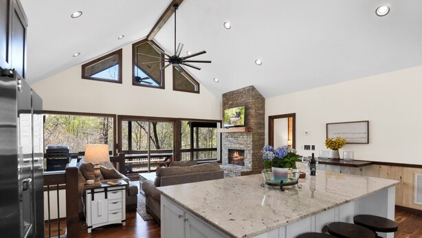 A spacious kitchen with a large island, a stone fireplace, and a view of the outdoors.