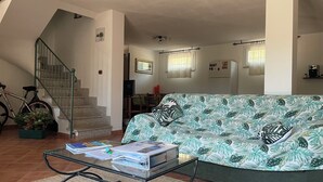 Ein Wohnzimmer mit einer Couch, einem Glastisch, einer Treppe und einem Fahrrad.