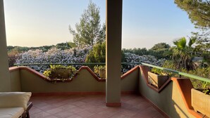 Ein Balkon mit Fliesenboden, einer gepolsterten Sitzecke und Topfpflanzen.