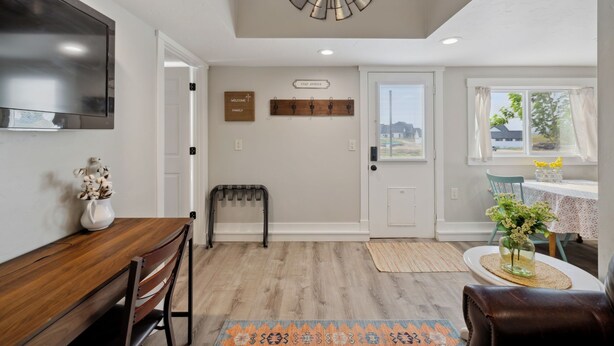 A modern interior with a wooden dining table, a bench, a mounted TV, a ceiling fan, and a view of the outdoors through a window. - Charming barndominium with children's loft in quaint Middleton, Idaho (Caldwell)