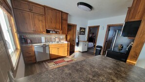 A kitchen with wooden cabinets, a granite countertop, and a built-in dishwasher. -  Authentic pioneer 
2 bedroom ranch farmhouse in beautiful Teton Valley Idaho. (Victor)