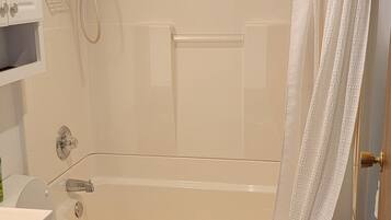 A bathroom with a bathtub, toilet, and a shower area.