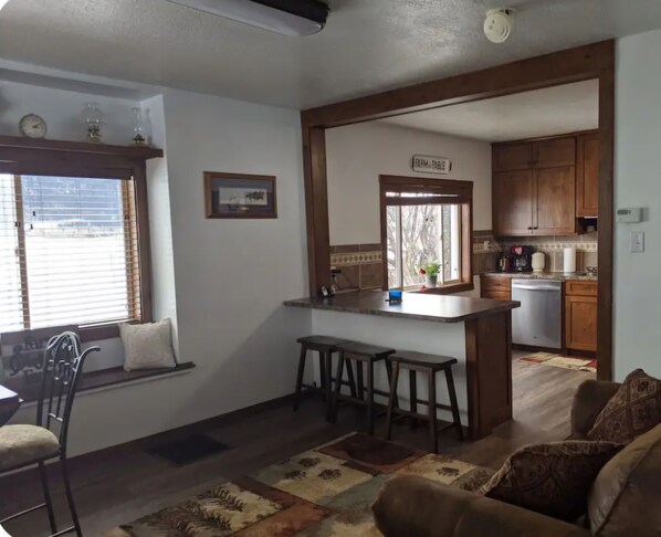 A compact living space with a kitchen area, a dining area with a window, and a sofa. - Authentic pioneer
2 bedroom ranch farmhouse in beautiful Teton Valley Idaho. (Victor)