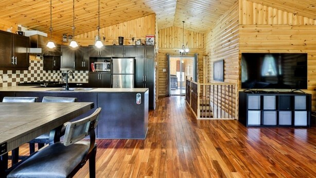 Una cabaña de madera espaciosa con cocina, comedor y televisor.