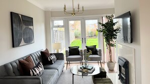 Una sala de estar moderna con un sofá gris, dos sillones, una mesa de centro y una chimenea.