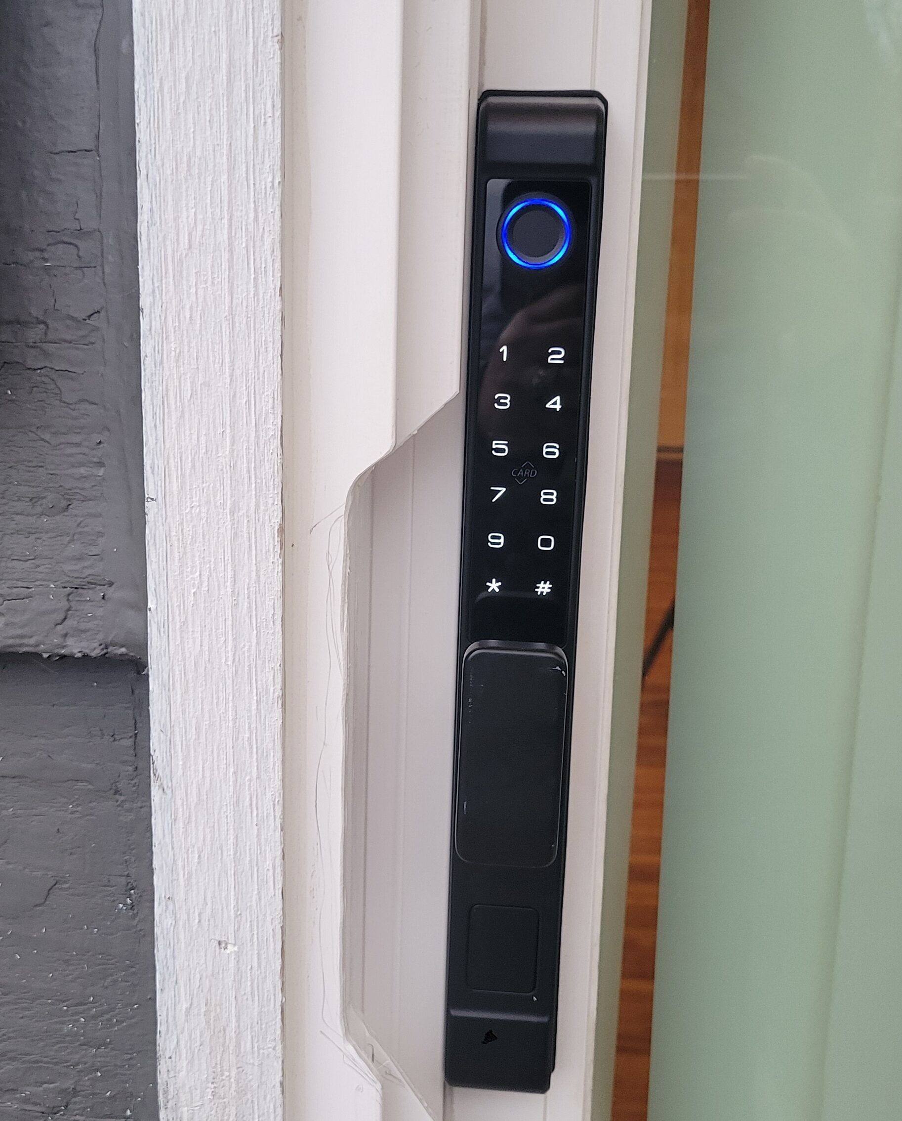 A keypad door lock with a blue illuminated button, a numeric keypad, and a card slot.