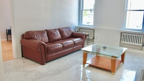 Ein geräumiges Zimmer mit einer braunen Ledersofa und einem Glastisch.