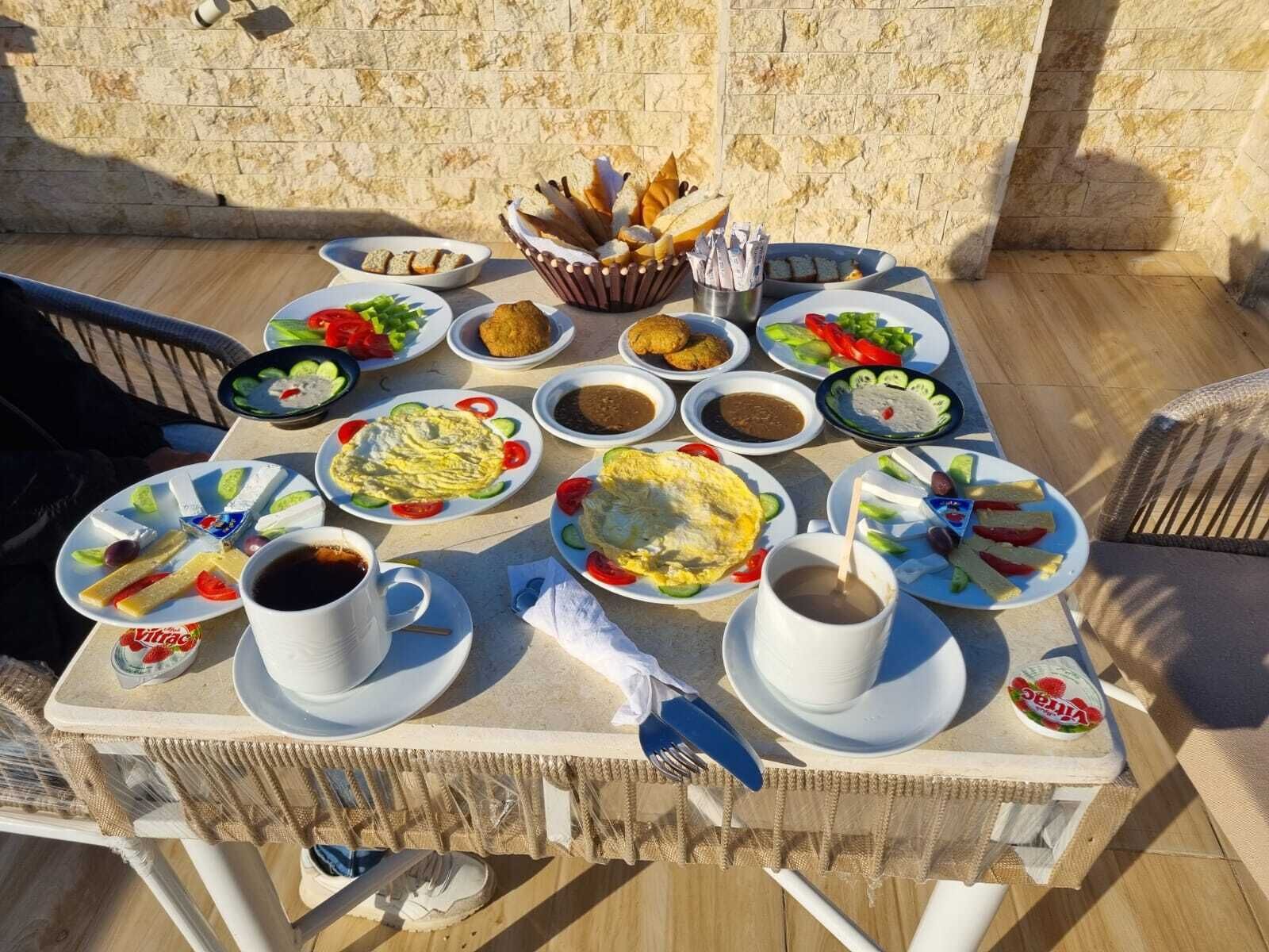 A table set with various dishes, including bread, salads, and a cup of coffee, on an outdoor patio.