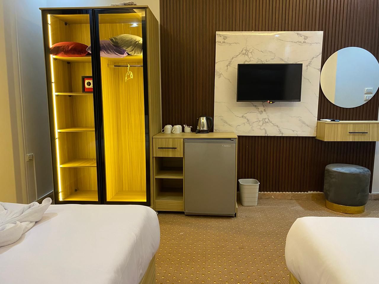 Ett hotellrum med två sängar, en minibar, en tv och ett litet kylskåp.