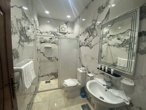 Un baño moderno con salpicadero de mármol, un espejo grande, un lavabo y una cabina de ducha.