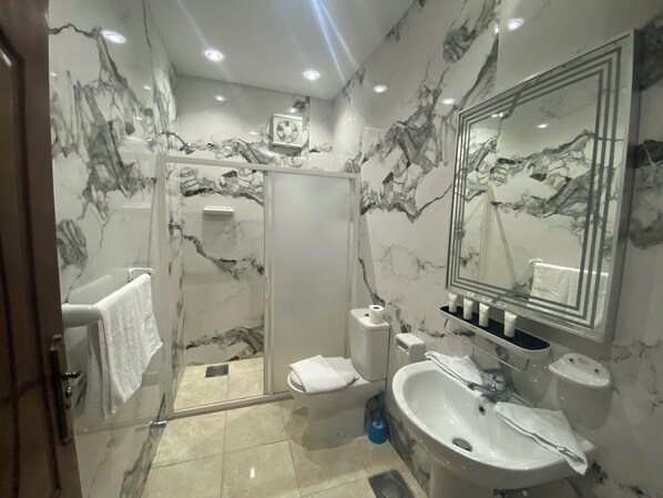 A modern bathroom with a marble backsplash, a large mirror, a sink, and a shower enclosure. - Rehana Pyramids Hotel (Giza)
