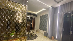 Un hall d’entrée moderne avec un mur orné d’un motif géométrique, un comptoir d’accueil et un espace détente doté d’une table ronde.