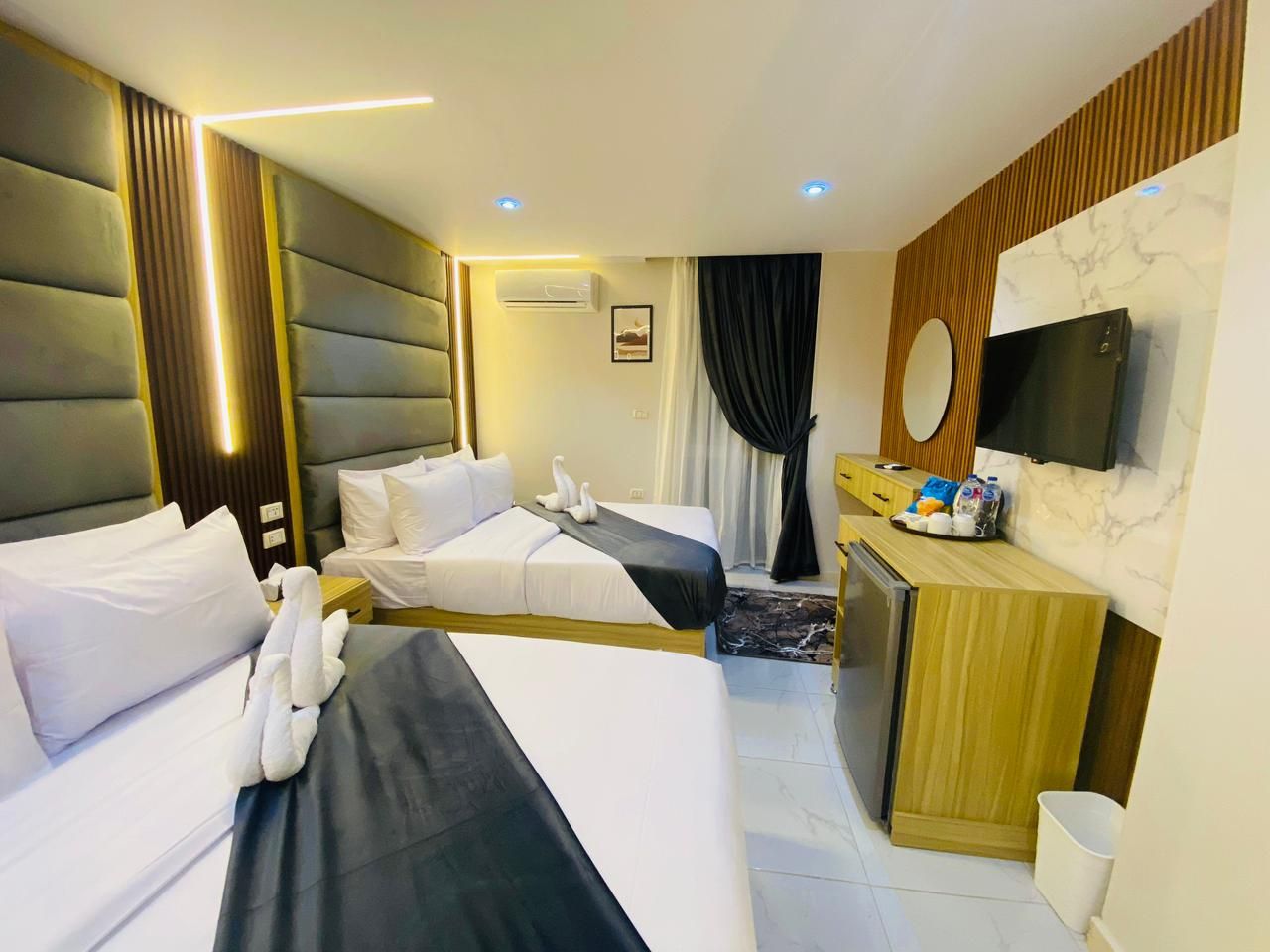 A hotel room with two beds, a desk, a television, and a bathroom.