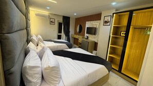 Une chambre d’hôtel avec deux lits, un bureau, une télévision et une armoire.