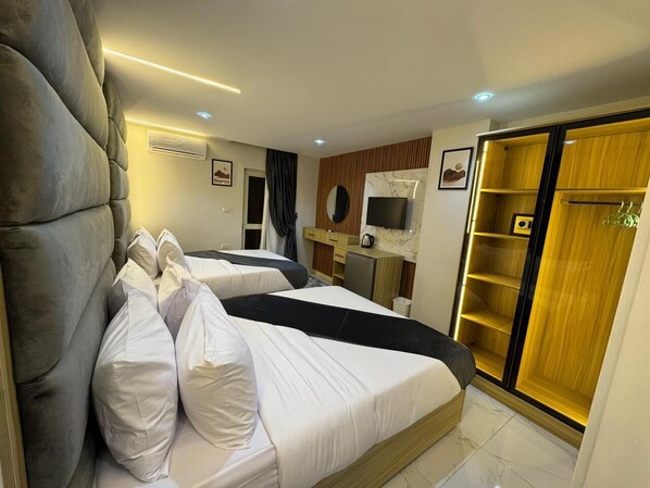 Una habitación de hotel con dos camas, un escritorio, un televisor y un armario.