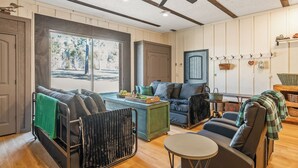 A cozy living room with a sofa, a dining table, and a ceiling fan.
