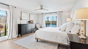 Une chambre dotée d’un grand lit, d’un ventilateur de plafond, d’une commode, d’une table de chevet et offrant une vue sur l’extérieur.