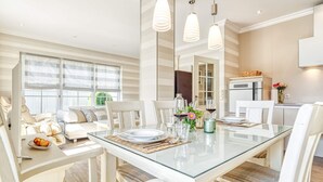 A modern dining area with a glass table, white chairs, and pendant lighting. - Rosenberg 27 - "Family-friendly vacation apartment in Zingst with garden and (Zingst)