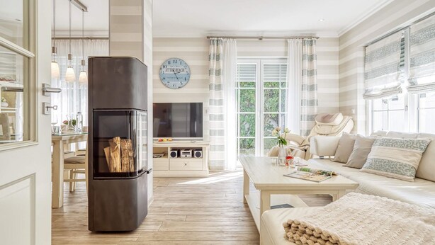 A modern living room with a wooden floor, a black refrigerator, a beige sofa, a coffee table, and a TV on a white wall. - Rosenberg 27 - "Family-friendly vacation apartment in Zingst with garden and (Zingst)