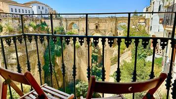 Un balcon orné de balustrades en fer forgé, donnant sur un pont de pierre historique et sur des bâtiments.