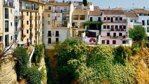 A residential area with multi-story buildings, balconies, and a rocky hillside with vegetation.
