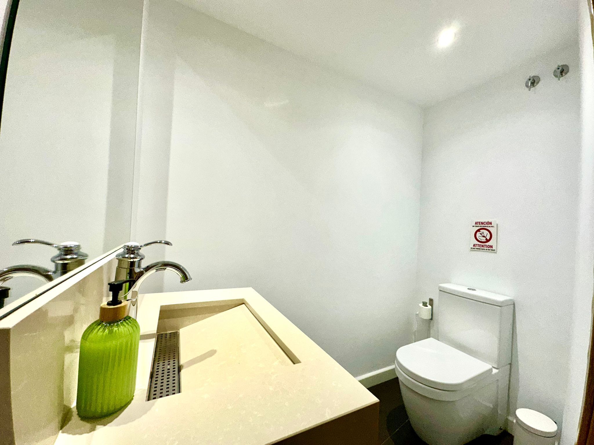 A small, modern bathroom with a sink, mirror, and toilet.