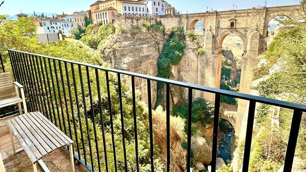 A balcony with a view of a historic stone bridge and buildings.