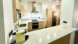 A modern kitchen with a marble countertop, stainless steel appliances, and wooden cabinetry.