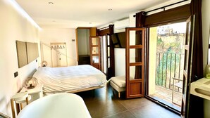 A bedroom with a bed, a bathroom with a bathtub, a balcony with a view, and a TV mounted on the wall.