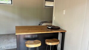Un petit coin cuisine avec un plan de travail en bois, deux tabourets et une fenêtre donnant sur un beau paysage.