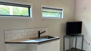 Une cuisine moderne avec des meubles blancs, un évier encastré et deux fenêtres.