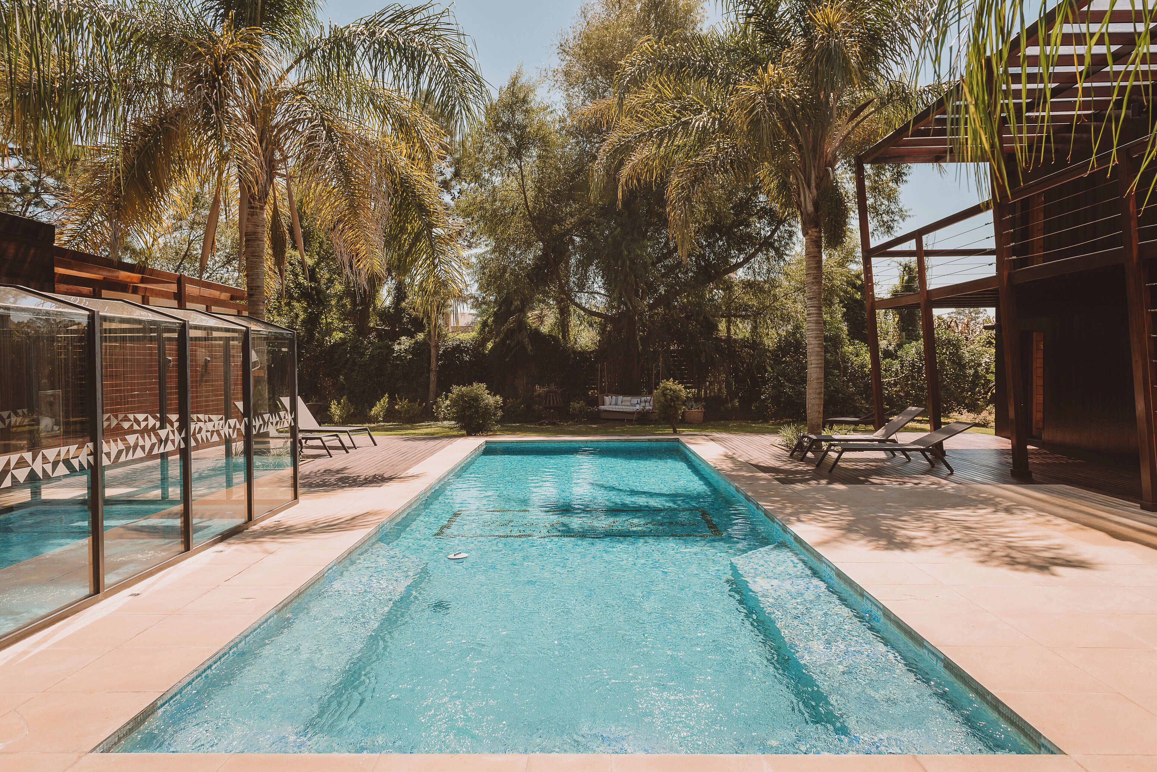 A rectangular swimming pool with clear blue water, surrounded by a tiled deck.