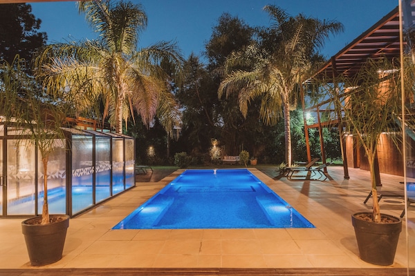 Una piscina techada, una piscina al aire libre, sombrillas