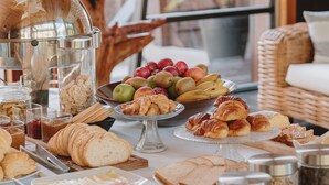 Una mesa de buffet con diversas opciones de comida, como frutas, pasteles y pan.