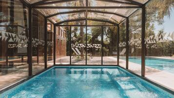 Alberca techada, alberca al aire libre y sombrillas en la alberca