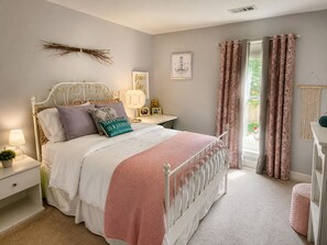 A bedroom with a bed, bedside tables, a lamp, a wall decoration, and a window with curtains.